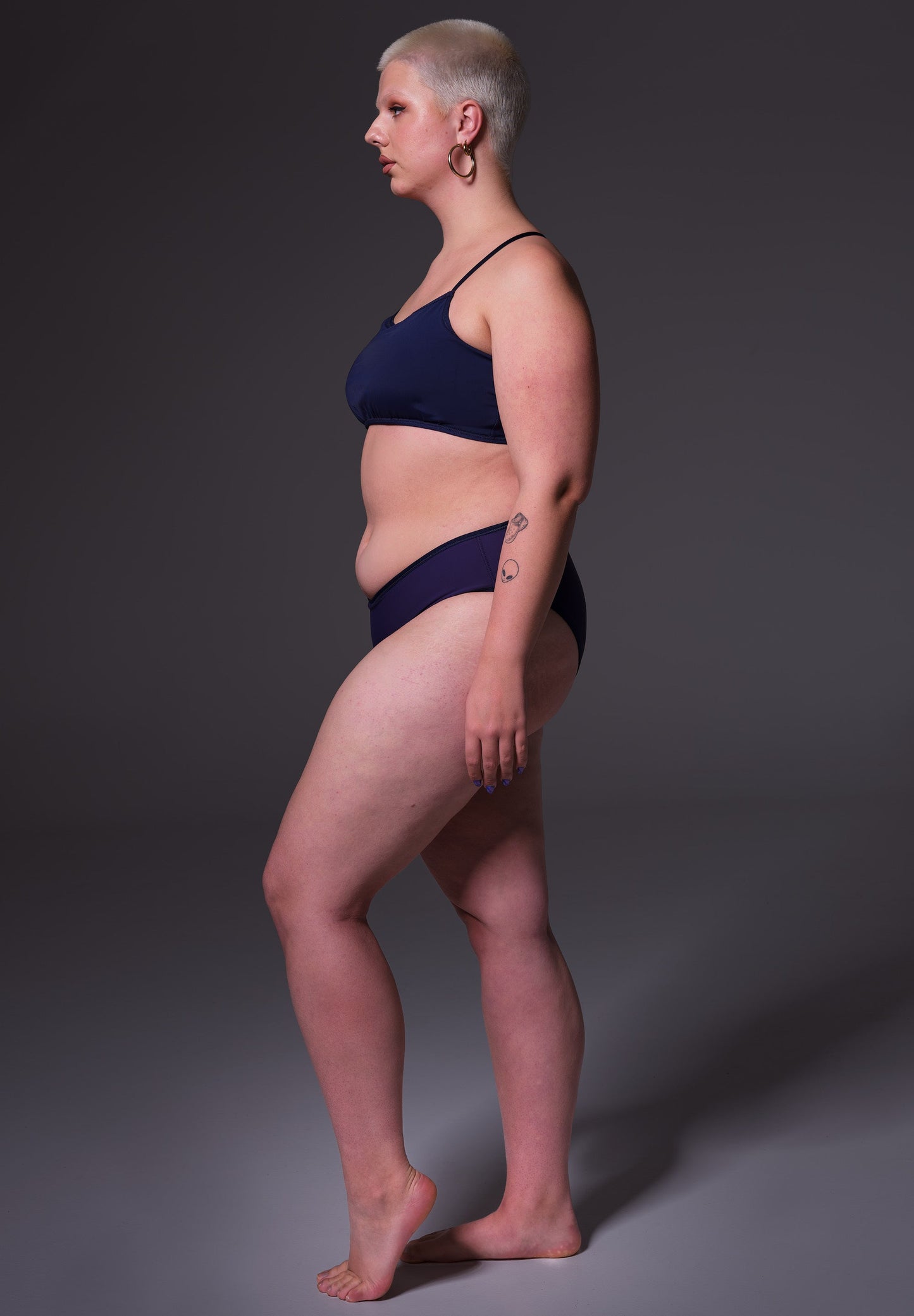 Side vief of Sasha, modelling the  Bikini Slip in dark blue, by UNTAG