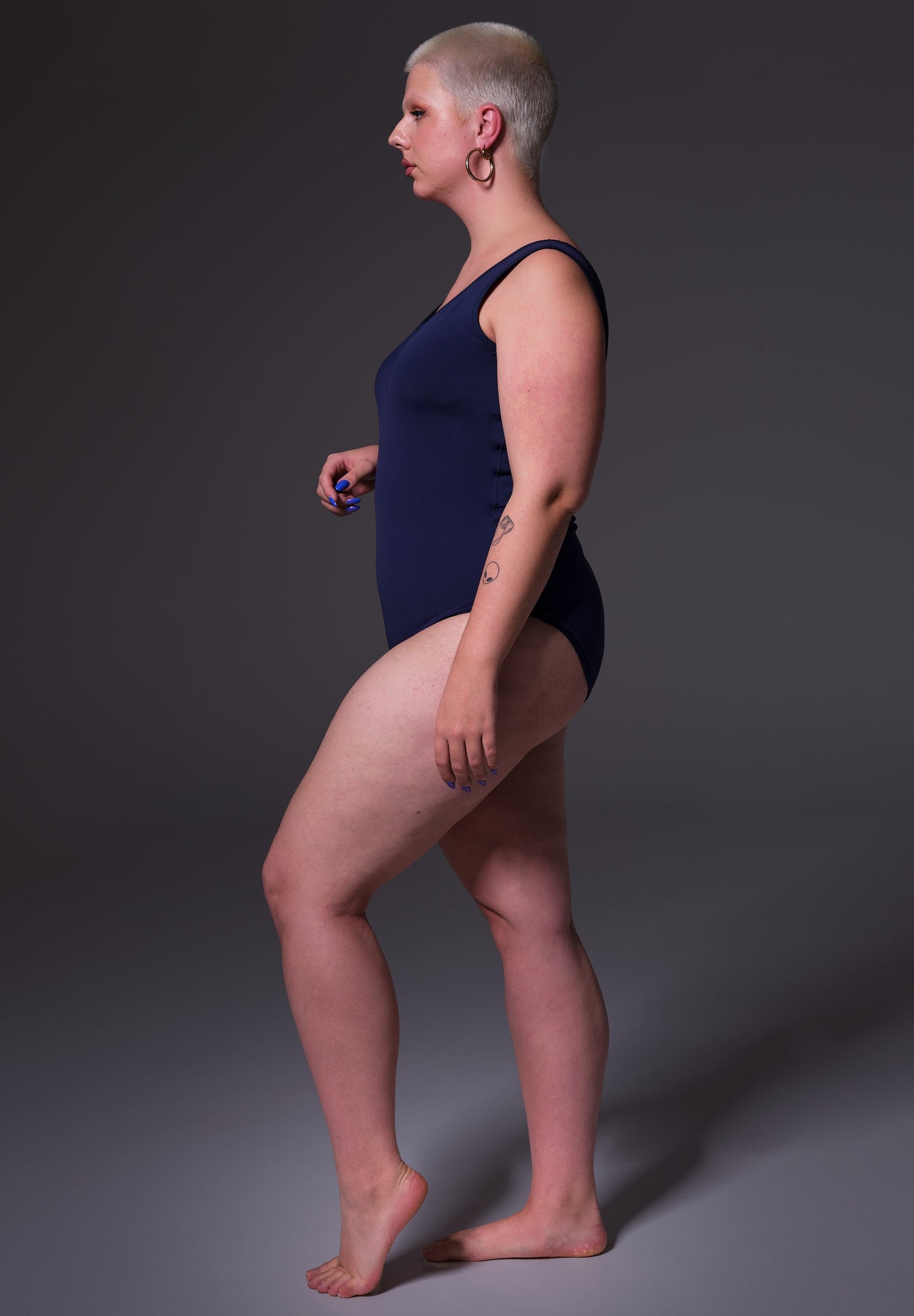 Side view of model Sasha wearing the Swimsuit dark blue, by UNTAG